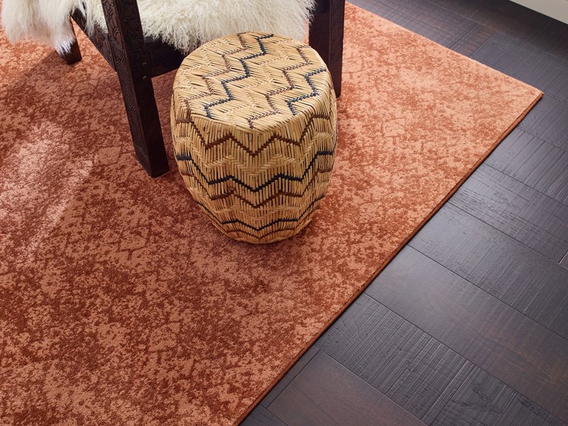 Room with dark hardwood flooring and an orange patterned area rug - Carpet binding by Capitol Carpet in Dalton