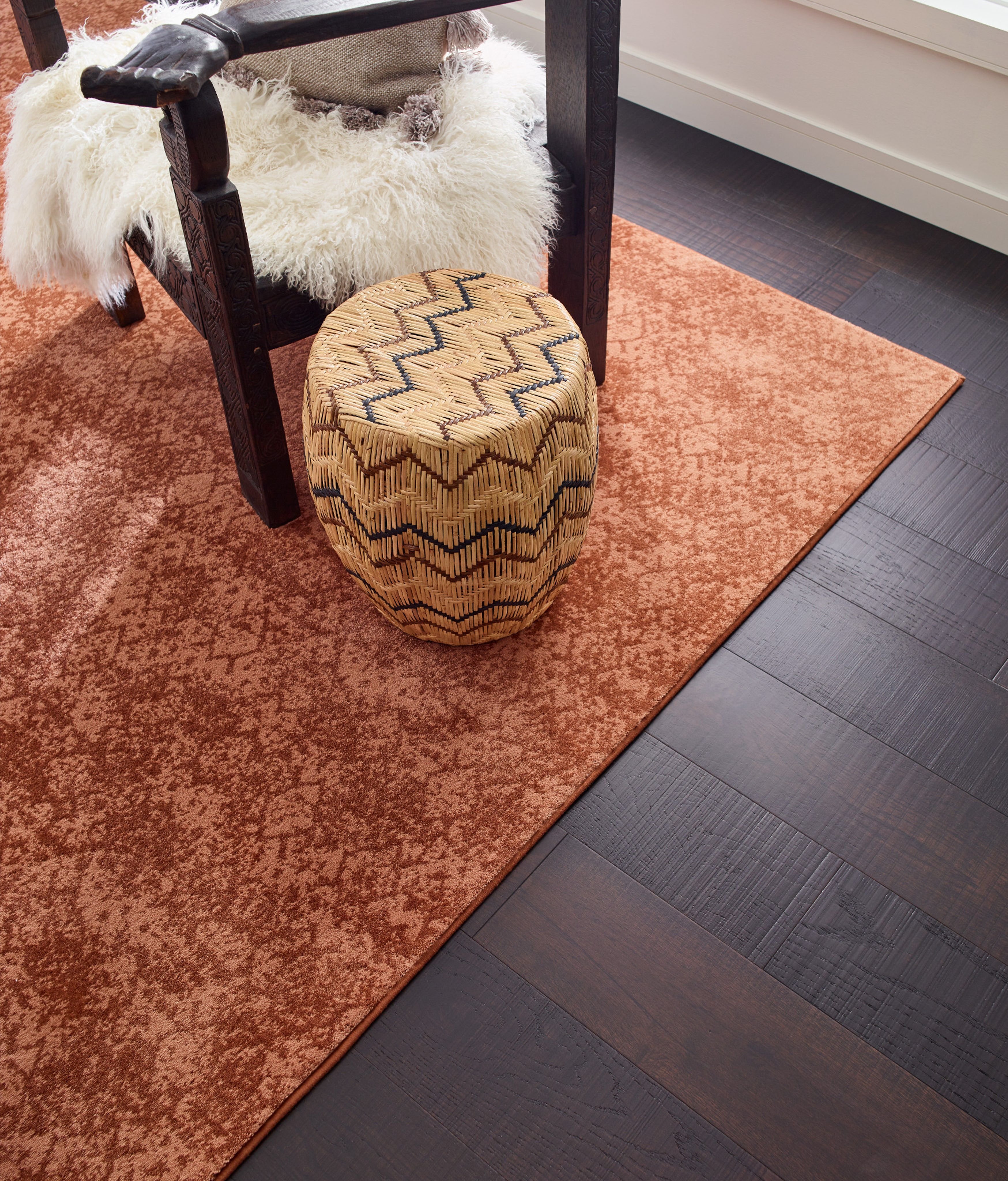 Room with dark hardwood flooring and an orange patterned area rug - Carpet binding by Capitol Carpet in Dalton
