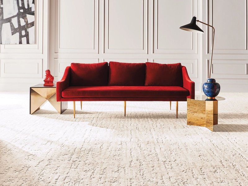 Bright living room with a red velvet couch and beige textured nylon carpet from Capitol Carpet in Dalton, GA